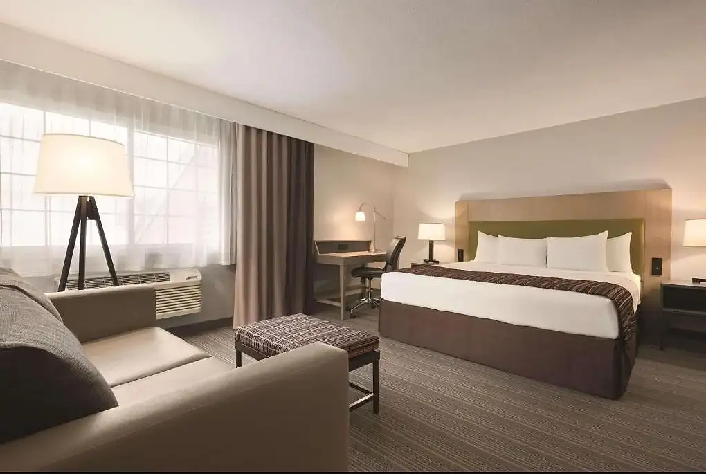 A king room with a sofa and a bench at the foot of the bed