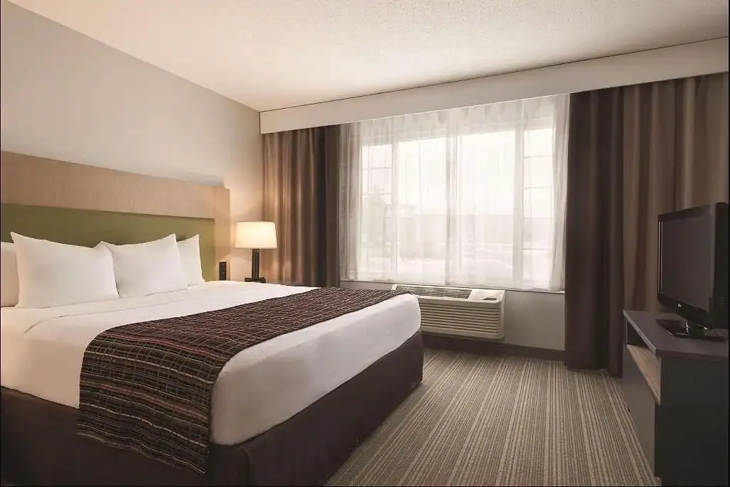 A king room with a wide window and full-length curtains