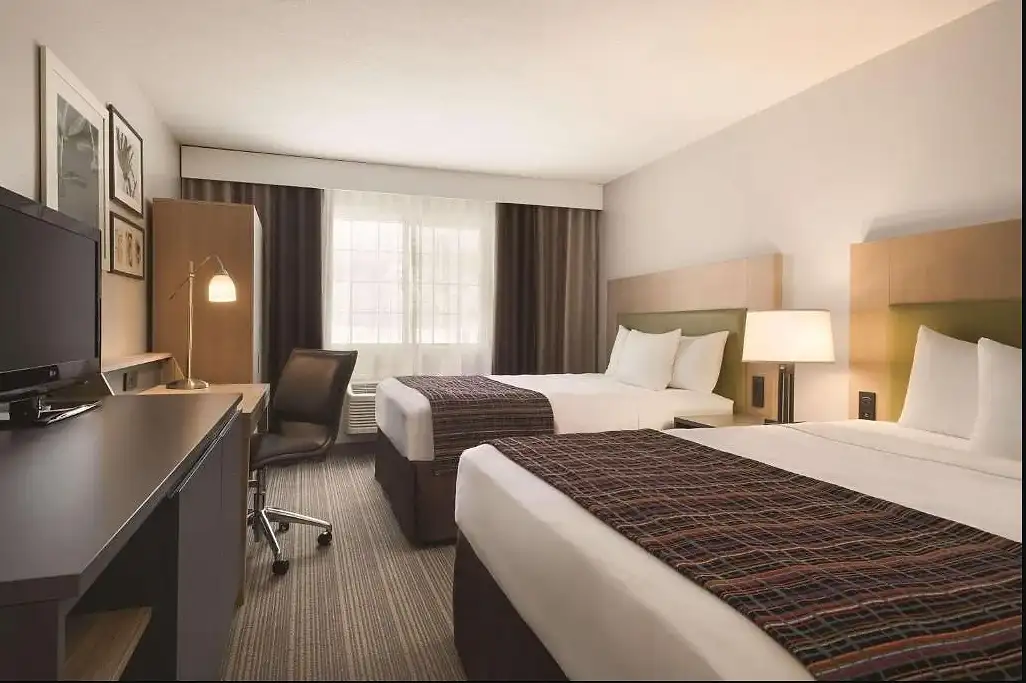A two queen room seen from the door, with the desk and window beyond the beds