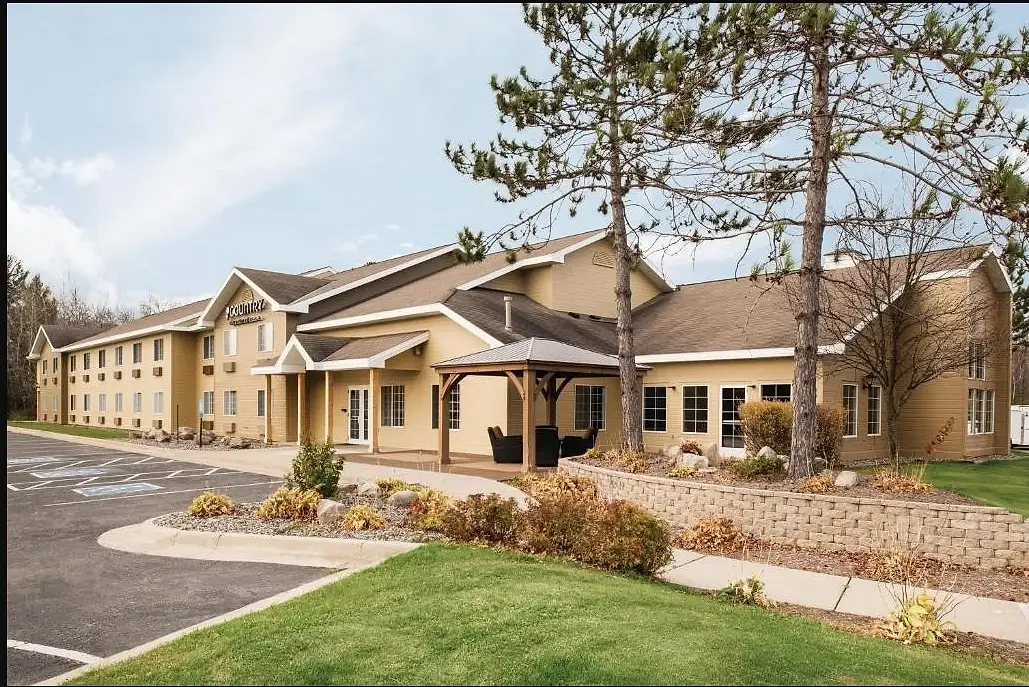The hotel from the parking lot, with the timber gazebo, terrace and mature pines along the front